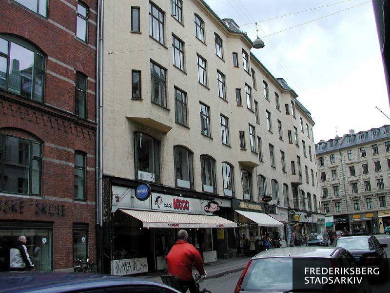 Hjørneejendommen og butiksfacader Gammel Kongevej 85 og Værnedamsvej 15-17 set fra Værnedamsvej. I forgrunden Café Viggo og lidt af naboejendommen Københavns Tekniske Skoles bygning