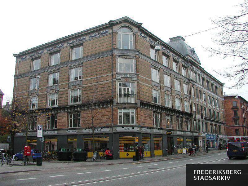 Gammel Kongevej 123-125 på hjørnet af Martensens Allé i november 2007. Foran Netto ses genbrugsbeholdere til glas, cykelstativer, ventende ved busstoppestedet og en postkasse ses til venstre