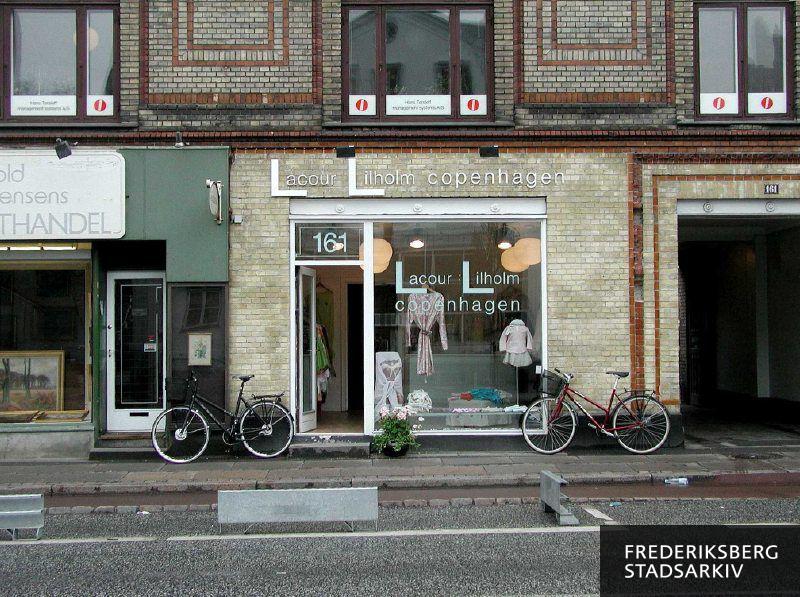 Butiksfacaden til LaCour Lilholm Copenhagen dametøjsforretning, indgangsdøren til kunsthandlen ved siden af og skiltning af virksomheden Hans Tørsleff management systems A/S i vinduerne på første sal