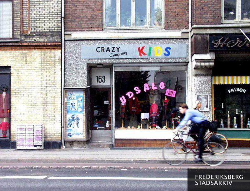 Butiksfacaden til børnetøjsforretningen Crazy Company Kids mellem en anden tøjforretning og en herrefrisør
