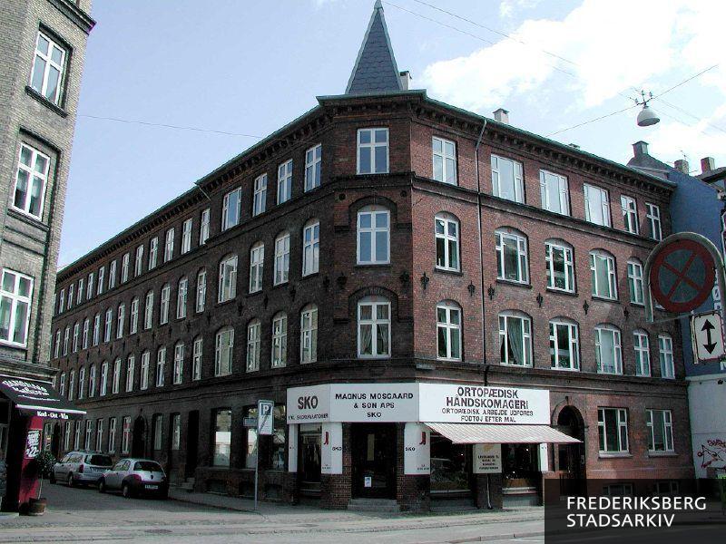 Ejendom med friser, bånd, tårn og spir med butiksfacade til Magnus Mosgaard & Søn Sko