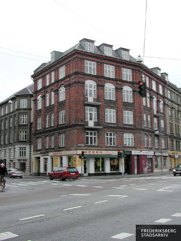 Hjørneejendommen Smallegade 56 og Nordre Fasanvej 2 med butiksfacader til Keeko Skrædderservice der også sælger tøj, Frisør Salon Kanarie, Pizzeria Bodrum og i naboejendommen solariet Top Sol
