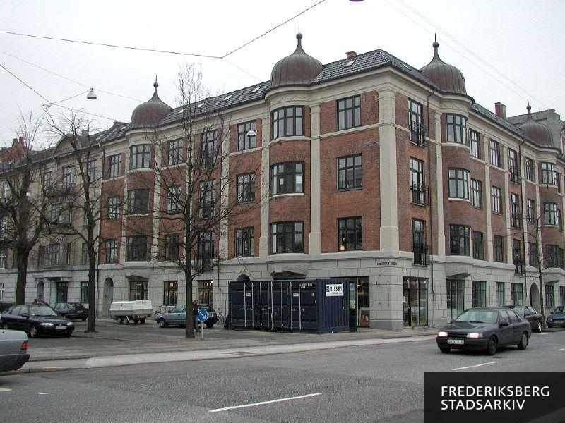 Hjørneejendommen Jacobys Allé 2-4 og Pile Allé 15 med fire brede tårne og spir over de fire søjler med karnapperne. Her fotograferet i januar 2003 med en container fra Bilsby og en trailer parkeret foran