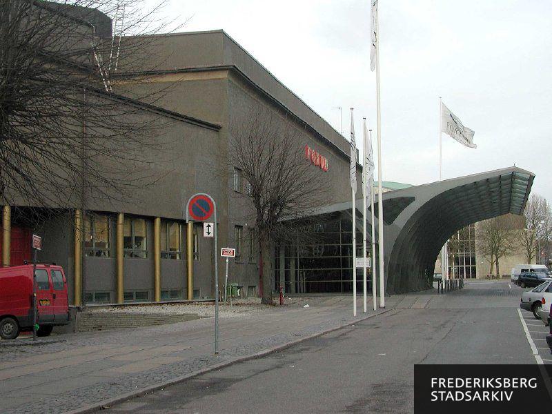 Hovedindgang med overhængende halvtag til publikum til Forum Copenhagen på Julius Thomsens Plads 1 i 2004. Til venstre ses en varevogn i indkørslen for udstillere og leverandører. I baggrunden til højre ses foyeren til Radiohusets Koncertsal, få år senere overtog Det Kongelige Danske Musikkonservatorium koncertsalen