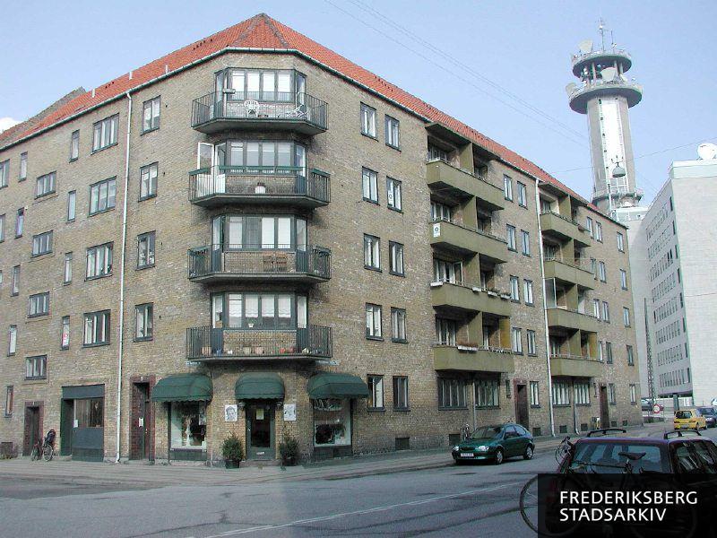 Mariendalshaves husnumre på Kronprinsesse Sofies Vej 43-45, hushjørnet med altaner og frisørsalon, som har adresse på Ane Katrines Vej 2. Til højre ses Teletårnet med udstyr og store dele af bygningerne til det gamle telefonhus på Borups Allé, og en bil på nedkørslen fra Bispeengbuen ses også