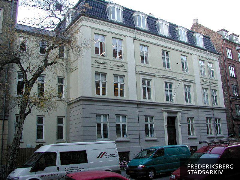 Kaptajn Johnsens Skole med flagstang i 2006. Foran ses et afløvet træ med en stor fuglerede. I forgrunden holder arbejdsvogne fra Hovedstadens Bygningsentreprise A/S og Malerfirmaet Petersen & Andersen A/S