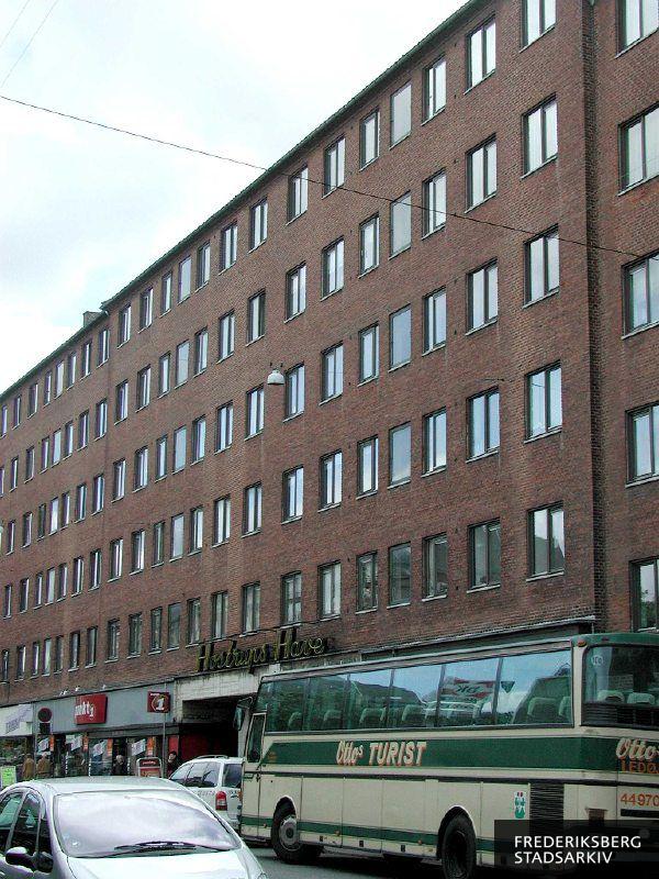 Indkørslen til Hostrup Have i nr. 8-10 med neonskilt over porten, på gaden ses en turistbus fra Ottos Busser