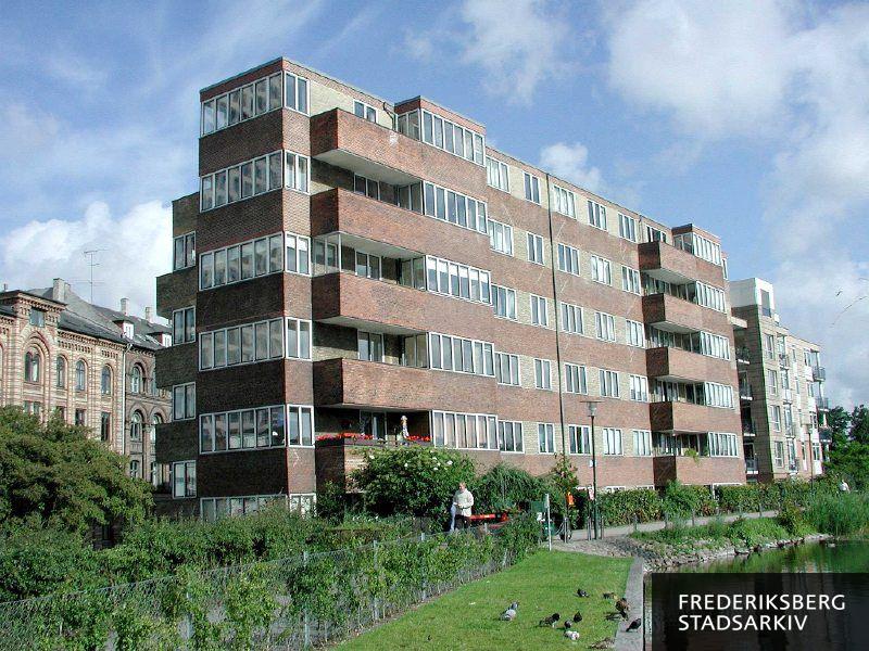 I midten Lagkagehuset, til venstre Vodroffsvej 5 og til højre Søfronten Vodroffsvej 4A-B. Tværgående, tofarvede striber i facadens udformning har ejendommene tilfælles. I forgrunden ses lidt af stien Svineryggen ved Sankt Jørgens Sø og fugle på søbreddens græs