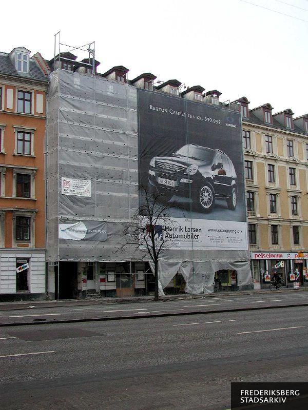 Ejendommen med reklamer for NP, outdoor Media og Henrik Larsen Automobiler på stilladsets plasticinddækning under renoveringen i december 2005