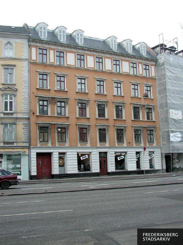 Ejendommen med fordakninger over vinduerne og fyldningsdøre i porten, der udstilles kakkelovne og brændeovne fra Pejseforum i stueetagens butiksvinduer