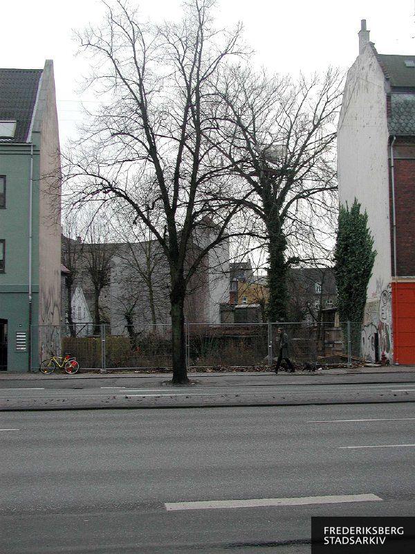 Ubebygget grund med træer, hegn og graffiti, der er rester af en hule i et træ i december 2005