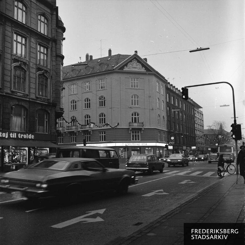 Lyskrydset Rolighedsvej, Godthåbsvej 2 og Falkoner Allé med trafik, børnetøjsbutikken Tøj til trolde og en bank på hjørnet i december 1977