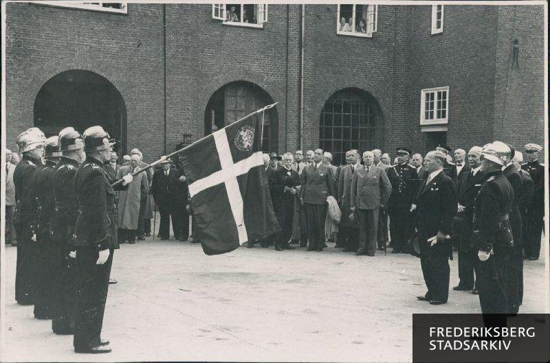 Ved faneindvielse af den nye korpsfane i forbindelse med brandvæsenets 75 års-jubilæum. 
På billedet ses til venstre for fanevagten, bl.a.: pensioneret res. sprf. Selsted, pensioneret maskinmester P. A. Pedersen, pensioneret brandmand nr. 8 Hansen.
til højre for fanevagten ses pensioneret brandfuldmægtig I. K. Bjerregaard med fipskæg og foran fanen ses borgmester Fischer.