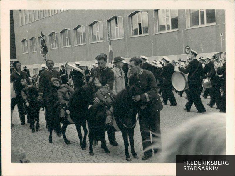 Parade gennem Bergen på den norske nationaldag, hvor Frederiksberg og Bergens brandvæsens musikforeninger deltog. I baggrunden ses musikkorpset og dannebrogs-fanen.