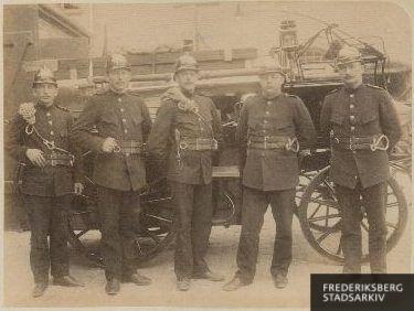 Brandmænd foran et af brandvæsenets køretøjer på stationen på Howitzvej.
Fra venstre ses brandmand nr. 41 Broholm, kusk nr. 3 Jacobsen, brandmændene nr. 23 Theodor Nielsen, nr. 31 Valdemar Petersen og Chr. Caspersen.