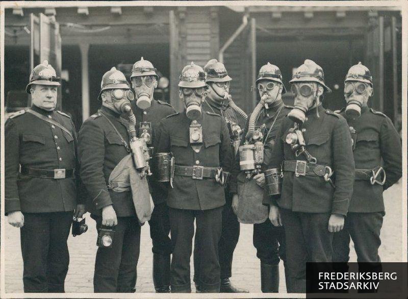 Syv brandfolk i uniform og iført masker, såkaldte Draeger-apparater model 1910. Uden maske til venstre ses sprøjtefører nr. 19 Andersen.