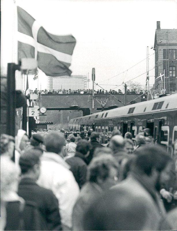 Den midlertidige Solbjerg Station med flagsmykket perron, fuld af mennesker.  I baggrunden en bro, der ligeledes viser en mængde personer. Bagest ses Frederiksberg Centret under opførelse.