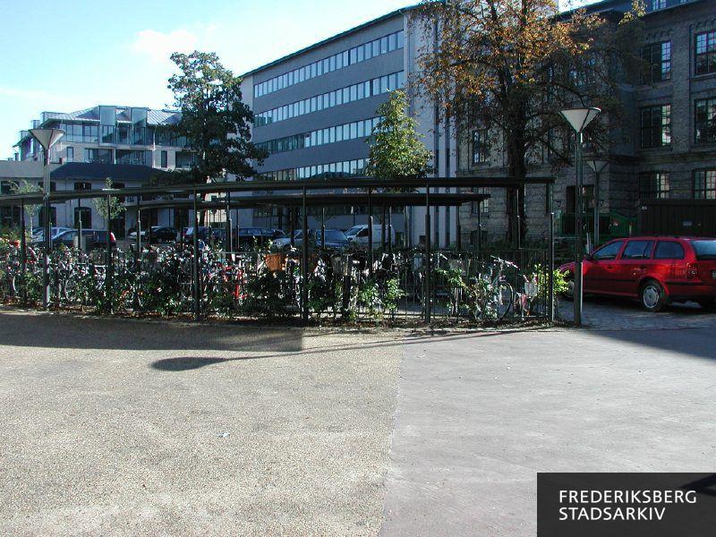 Gård med parkeringspladser og cykelstativer. De to bygninger til højre og i midten er indrettet til Copenhagen Business School CBS. Bygningen til venstre er ejerforeningen Fajancehaven