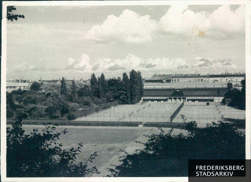 Udsigt fra Frederiksberg Slot over KB's tennisbaner i retning mod Pile Allé. Umiddelbart bag banerne kan man se KB's gamle tennisfaciliteter, der blev opført af klubben 1916-18 efter tegninger af arkitekt Einar Madvig.