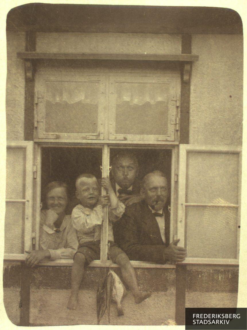 I det åbne vindue sidder Crilles Henriksen med frk. Løber til venstre og Fritz Hansen og 'Chaplin' til højre. Dagens fangst hænger under vinduet
