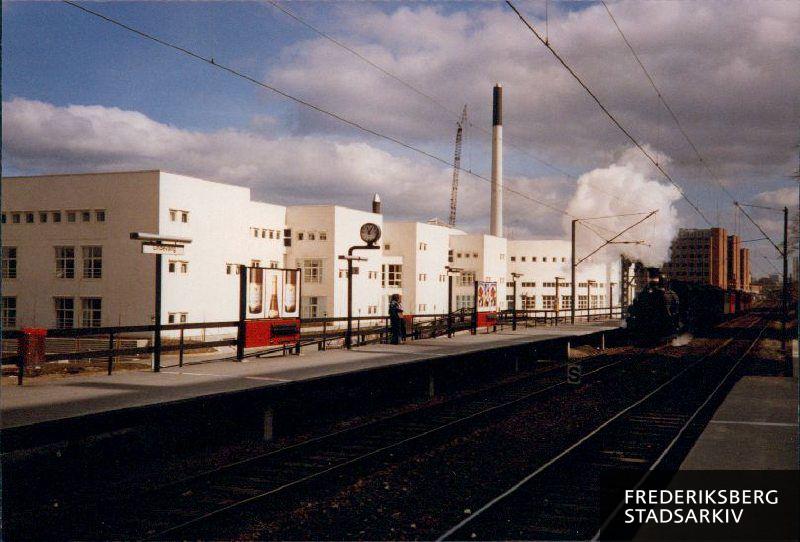 Udsigt fra Lindevang Station mod handelshøjskolen, dalgas have 15. Frederiksberg Varmeværks høje, hvide skorsten på Fabrikvej 38 ses til højre. Den røde bygning i baggrunden er Frederiksberg Tekniske Skole på Fabriksvej 5