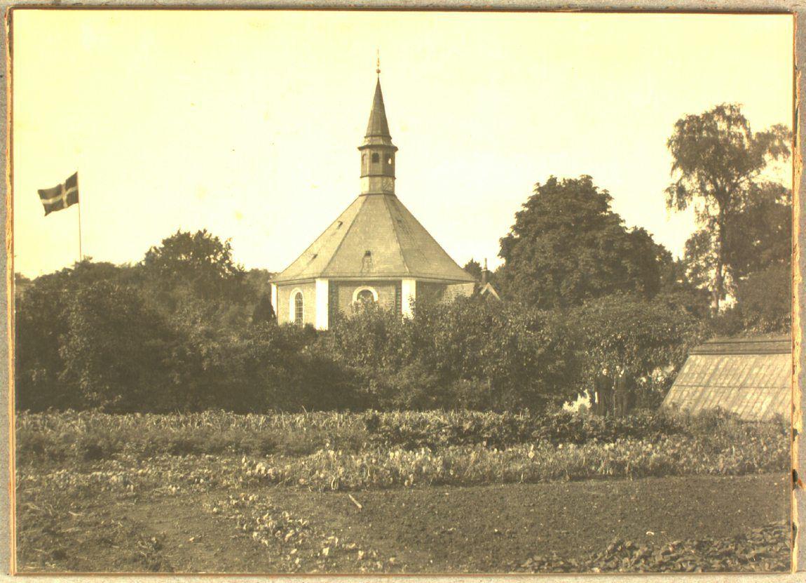 Frederiksberg Kirke, set fra præstegårdens have. Et drivhus anes til venstre