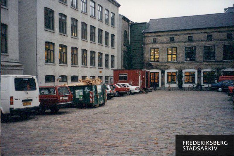 Udsigt til parkeringsplads bag bygninger på Danasvej og Danasvej Bibliotek
