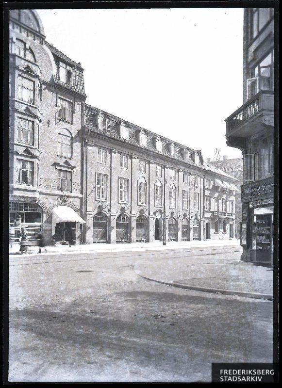 Etagebyggeri, der er opført efter tegninger af arkitekt Gotfred Tvede (1863-1947). Bygningen blev præmieret af Frederiksberg Kommmune i 1908.
Til højre er Sørensens boghandel på hjørnet til Madvigs Allé