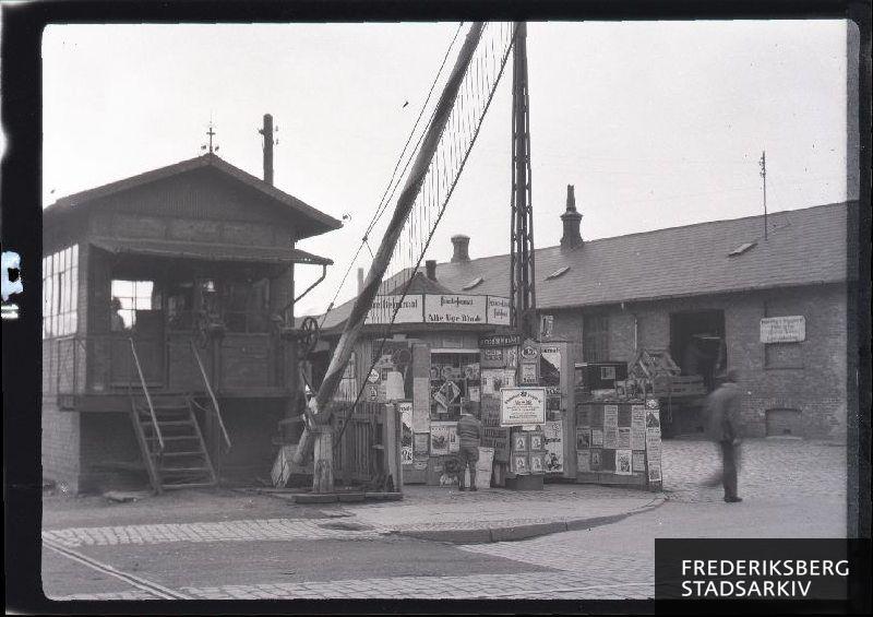 Bomhus med jernbanebom og kiosk ved  Frederiksberg Station Falkoner alle 21, F. DSB pakhus og godsindleveringsted på rampen i baggrunden