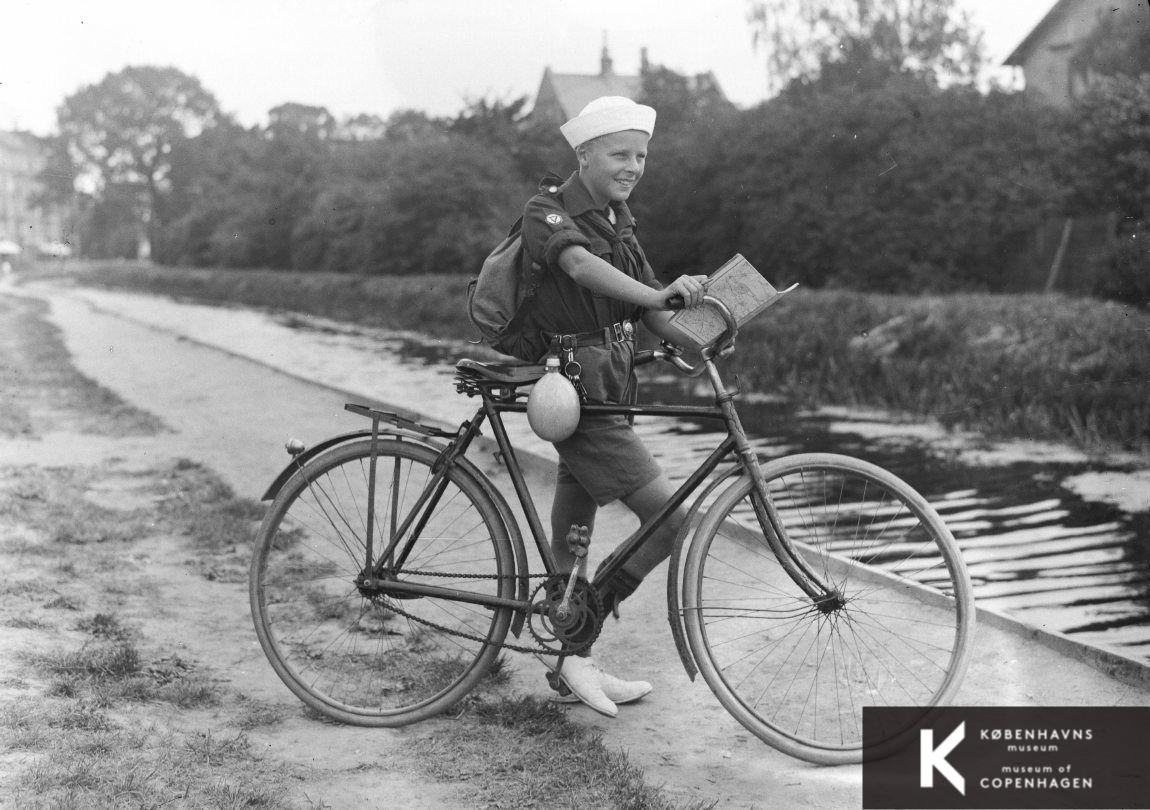 Dreng i spejderuniform på cykel