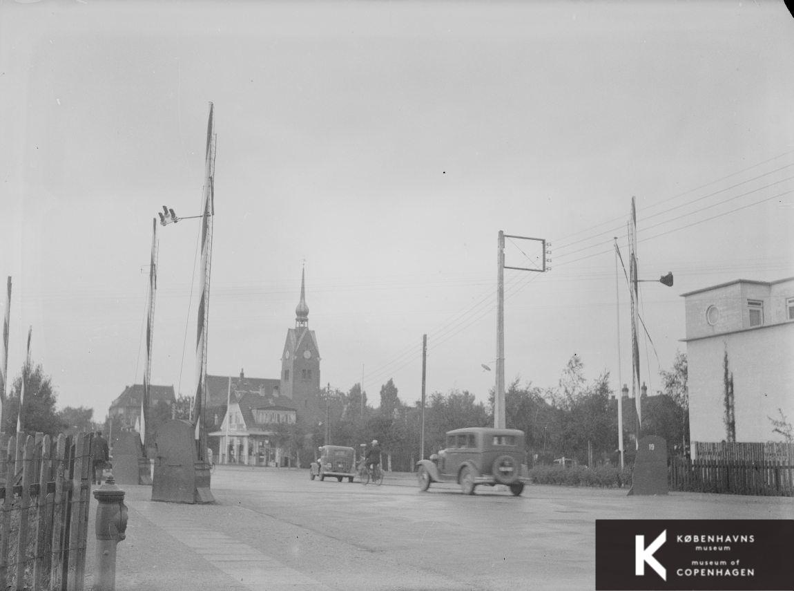 Vej med kirke i baggrunden og funkisvilla i højre side