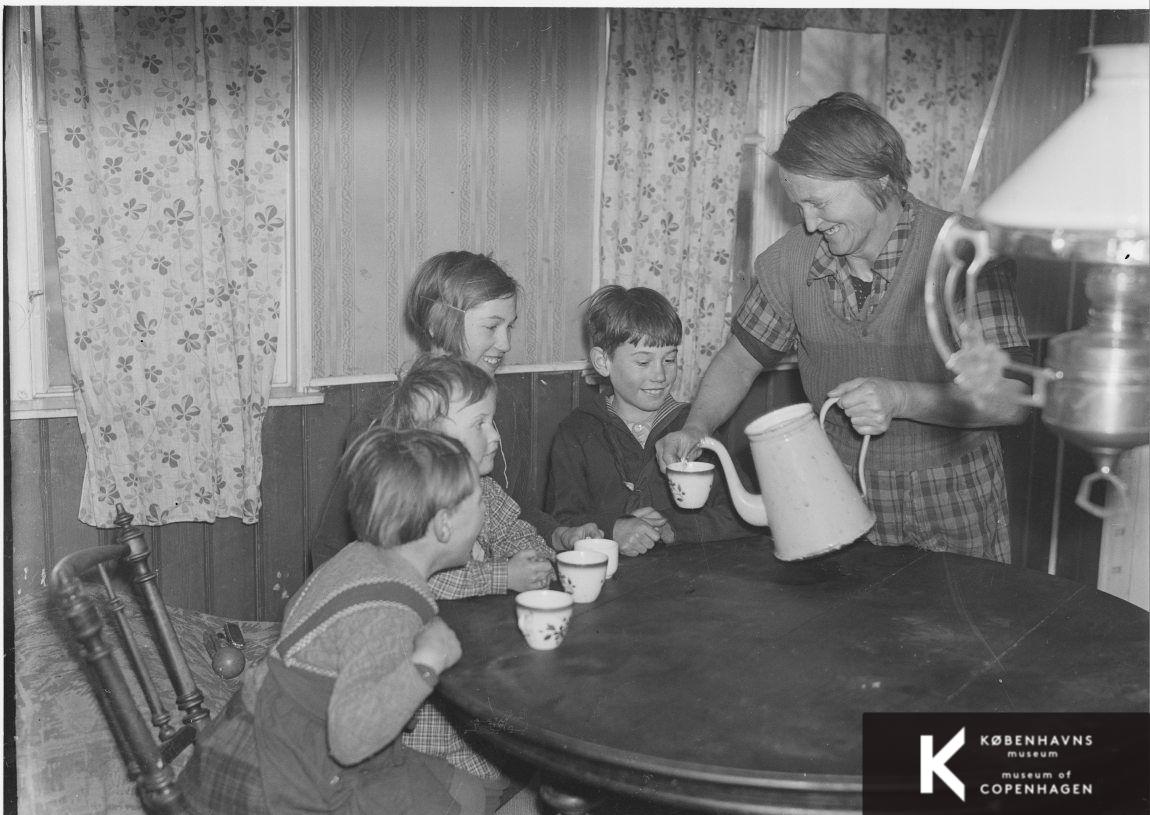 En mor serverer vand i kaffekopper for børnene