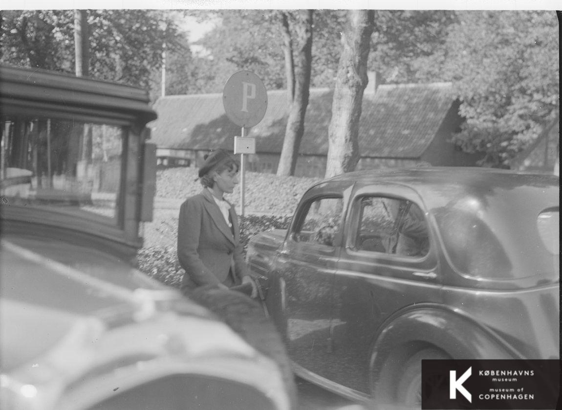 Ung kvinde stående mellem parkerede biler