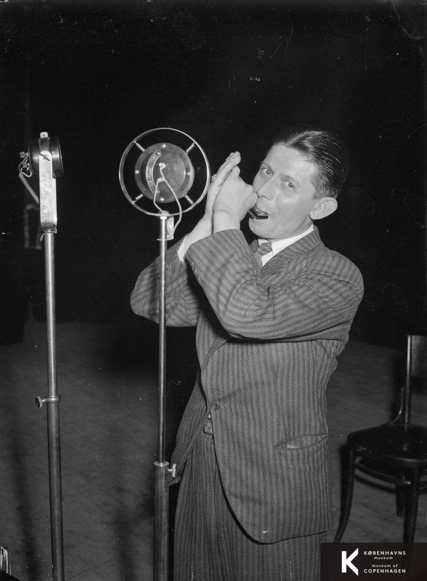 Ung mand spiller på mundharpe i en mikrofon.